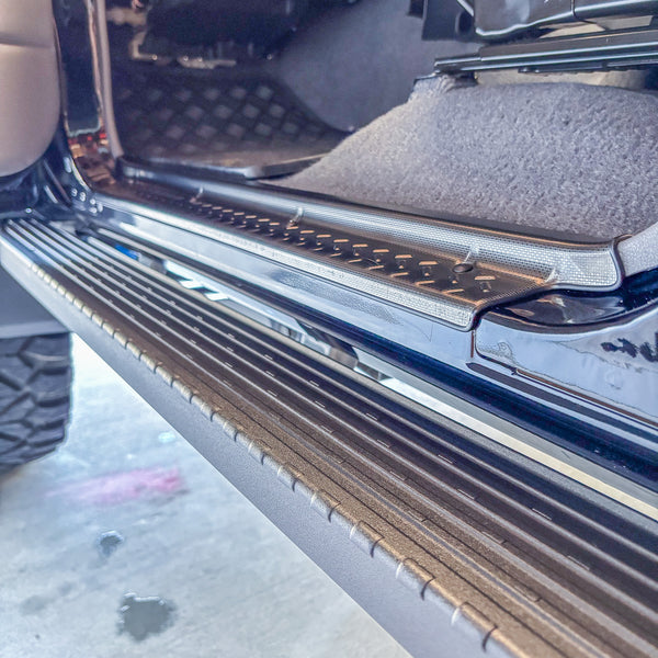 Stainless steel door sill trim installed on LandCruiser front door, diamond-plate floor mat visible
